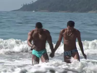 Zwei dunkelhäutige Hengste vögeln am Strand und saugen stramme Schwänze
